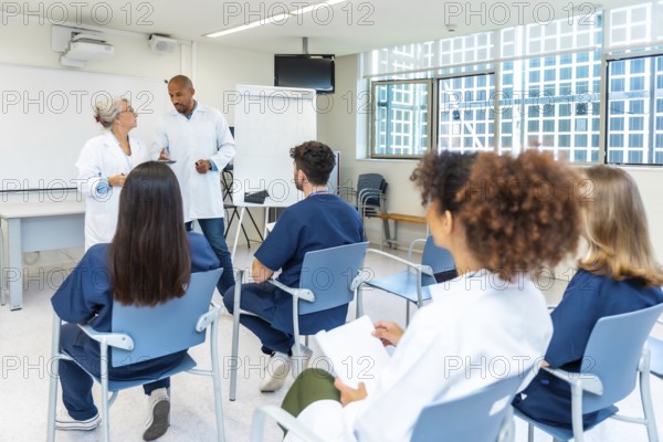 Doctors and nurses listening to senior colleagues giving presentation during medical conference in