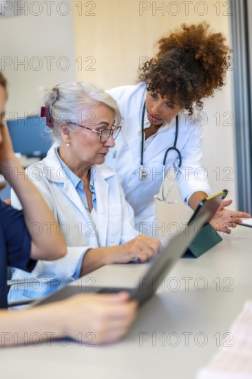 Medical professionals collaborating on a tablet, discussing patient cases and sharing expertise