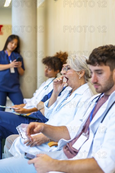 Exhausted doctors and nurses yawning and sitting in a hospital corridor, waiting for patients after