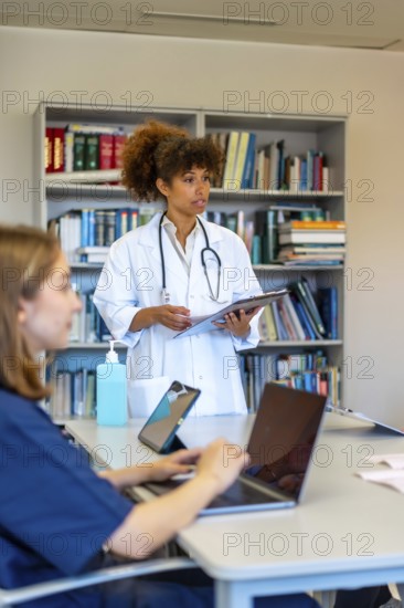 Doctors and nurses using laptops and tablets during a medical briefing, discussing patient charts