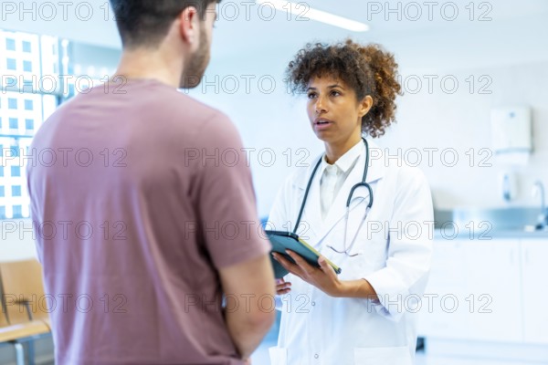 Doctor holding a tablet while explaining a diagnosis to a patient in a bright, modern hospital