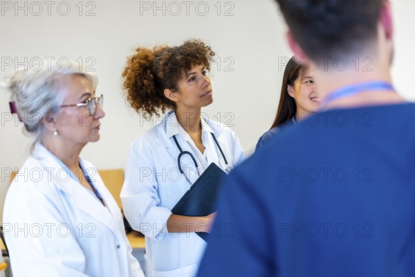 Doctors and nurses engaging in a medical staff meeting, attentively listening to a speaker while