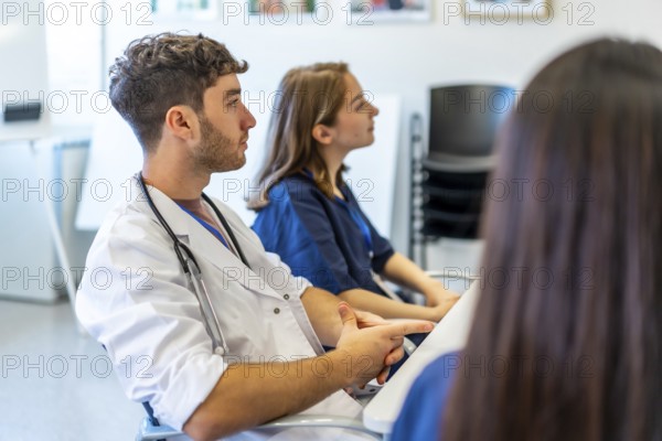 Medical professionals attending a conference in a hospital meeting room, listening to a