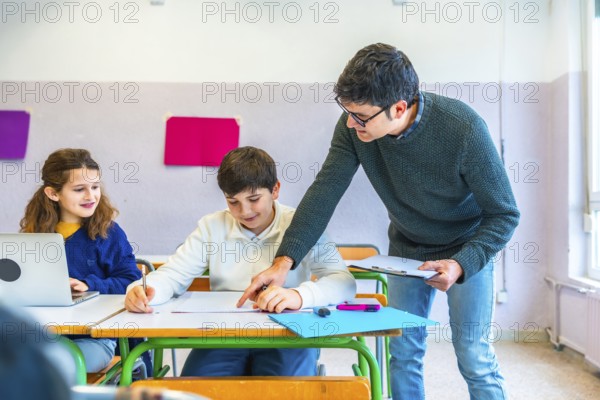 Teacher assisting students in the classroom, explaining concepts and correcting exercises while