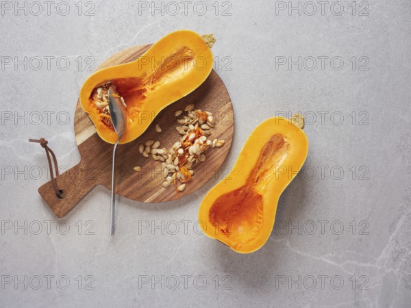 Remove the seeds from a raw butternut squash cut in half using a metal spoon. Cooking techniques