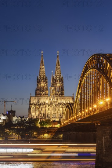 Cologne Cathedral, illuminated in the evening. Hohenzollern Bridge, railway bridge over the Rhine.