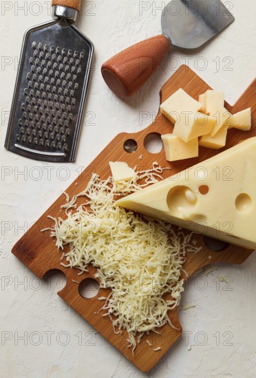 Grated cheese, Maasdam, on a cutting board, grater and cheese knife, close-up, no people