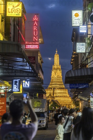 Wat Arun, Temple of Dawn at sunset with dark clouds. Boats on the Chao Phraya river. Tourist