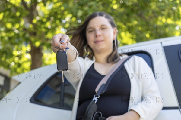 Proud businesswoman holding car keys in front of her new electric car, smiling with satisfaction