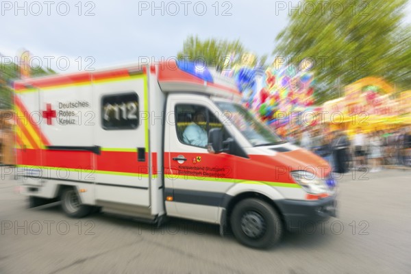 A German Red Cross ambulance drives quickly to an operation at the Cannstadter Volksfest, K