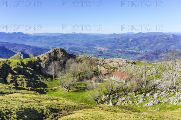Scenic view of a mountain landscape featuring a traditional basque building nestled among trees,