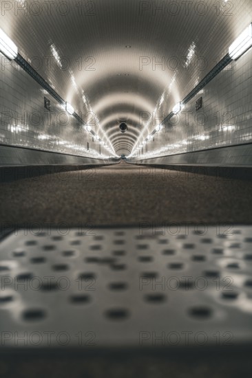 Long, illuminated tunnel with tiled walls from the ground perspective, old Elbe tunnel, Hamburg,