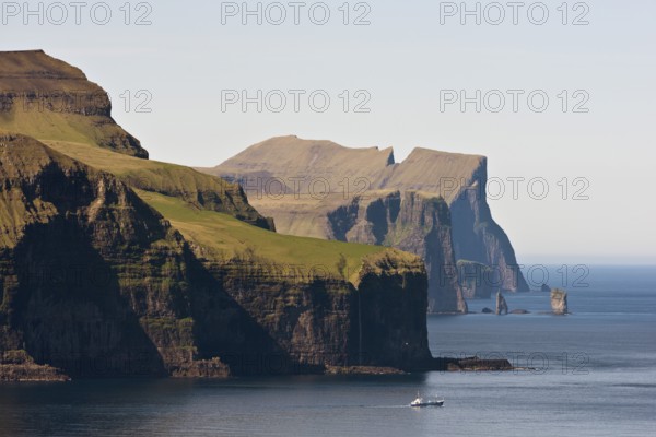 Fishing boat in front of Eysturoy, the basalt columns Risin and Kellingin at the back, Kalsoy,