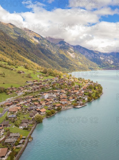 Alpine village on a lake with meadows and autumn colours, framed by mountains, Lake Brienz.