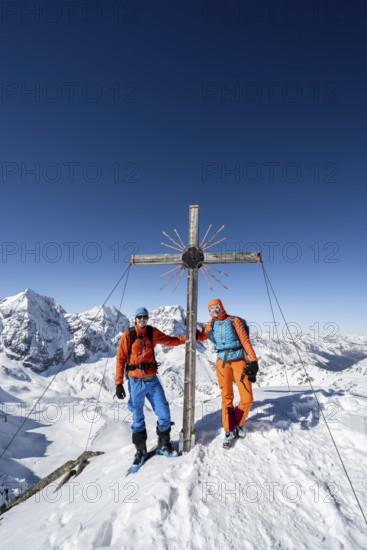 Two ski tourers at the summit cross on the summit of the Madritschspitze, mountain panorama with