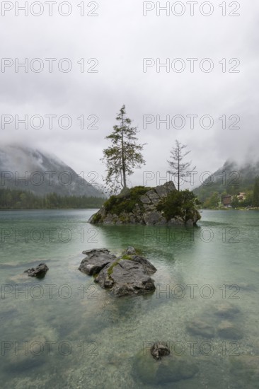 Hintersee near Ramsau, surrounded by forests and mountains under a cloudy rainy sky, fog,