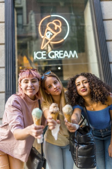 Vertical portrait of three diverse modern Women toasting with ice cream cones looking at camera in