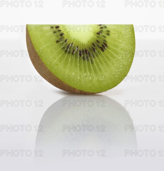 A kiwi slice, kiwi, kiwi fruit, Chinese gooseberry (Actinidia deliciosa) in front of a white