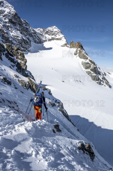 Mountaineer with skis at the fork Porta d'Es-cha, view of mountain peak Piz Kesch and glacier