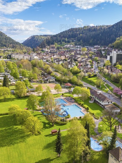 Overview of park with outdoor pool and town in the background in mountainous surroundings, Bad