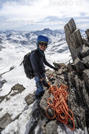 Mountaineer belaying with rope, climbing up a steep snow slope, belaying with rope, ascent to the