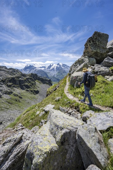 Mountaineer on hiking trail in mountain landscape, descent at Col du Louvie, view of the summit of