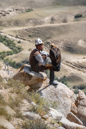 Traditional Kyrgyz eagle hunter hunting in the mountains in a dry landscape, near Kysyl-Suu, Issyk