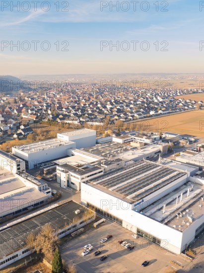 Aerial view of industrial plants next to a settlement under a blue sky in a rural setting,