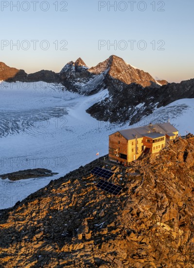 Atmospheric sunrise in a picturesque mountain landscape, alpenglow, aerial view, mountain hut