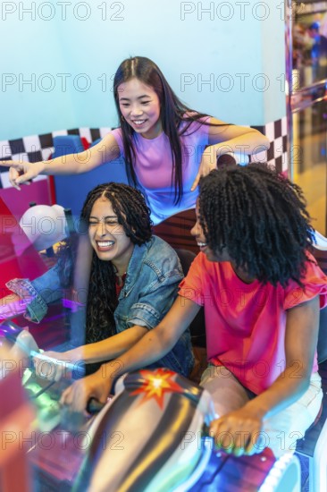 Group of female friends enjoying a lively gaming session, laughing and competing in a racing game