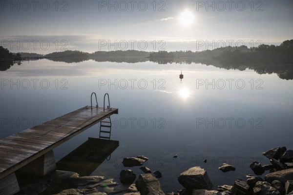 Wooden footbridge with ladder, sun reflected in the sea, morning mood, Kasnäsintie, Falkö Fjord,