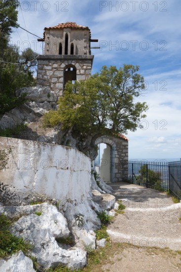 An old stone tower stands by the wayside under a clear blue sky, rock church of Smerna, Church of
