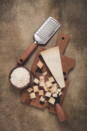 Freshly sliced and grated cheese, parmesan cheese, Gran gusto. Grana padano. on a wooden chopping