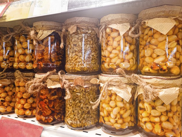 Jars of honey filled, with various nuts and seeds, are displayed on the store shelf, no people,