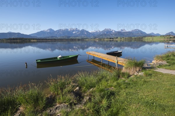Landscape with green and black boat at a lake, surrounded by mountain peaks, Hopfen am See, near