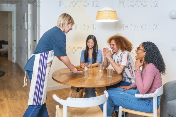 Happy multi ethnic friends are clapping hands while a woman is serving them food in a modern