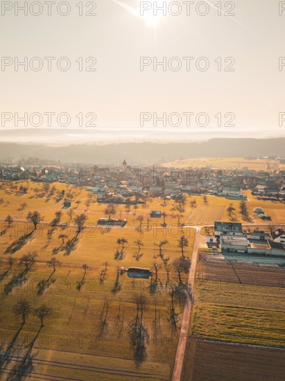 Extensive fields and trees with village in the background, in a misty autumn landscape, Neubulach,