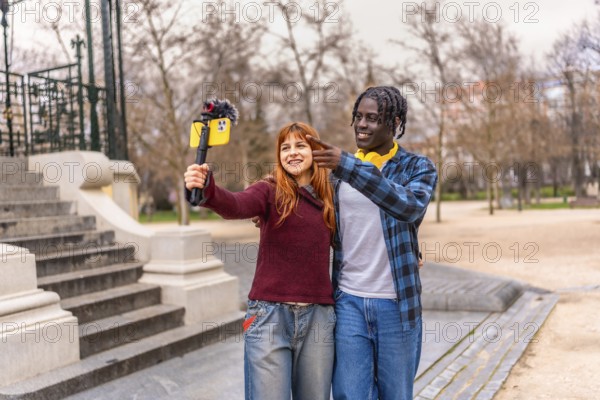 Two young content creators are recording a video for their vlog using a smartphone with a