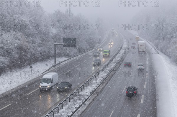 Snow-covered motorway with moving vehicles and snow-covered trees on the roadside, Winnenden,