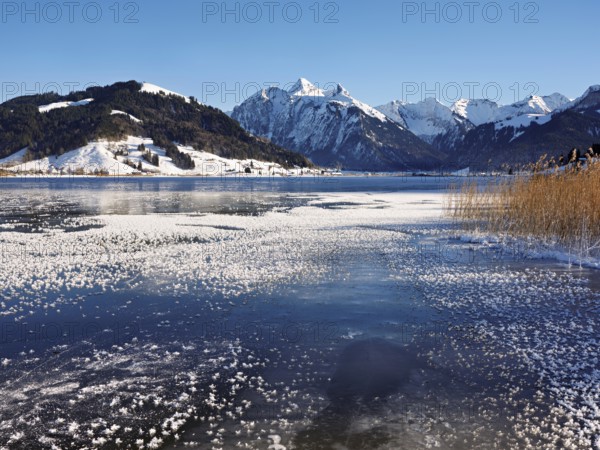 Frozen Sihlsee, reservoir, behind the snow-covered mountains Flübrig and Druesberg, Euthal, Canton