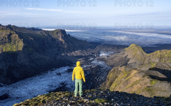 Young man, tourist in front of impressive landscape with glacier in the evening light, glacier