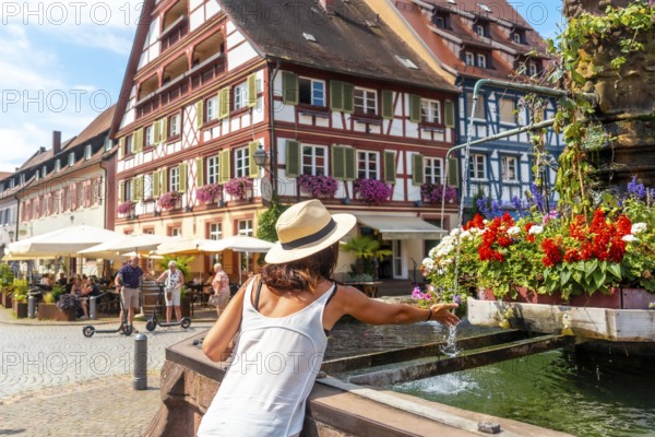A female tourist cooling off in the fountain in summer in the old town of Gengenbach in the Black