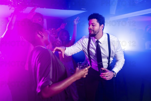 Businessman flirting with beautiful woman while holding alcoholic beverages and dancing at
