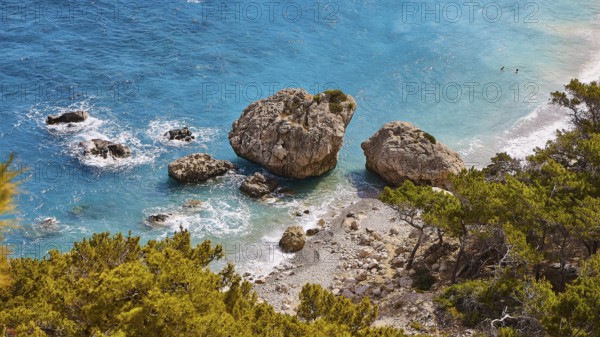 Large rocks in the turquoise sea on a coast overgrown with pine trees, Kato Lakkos Beach, still