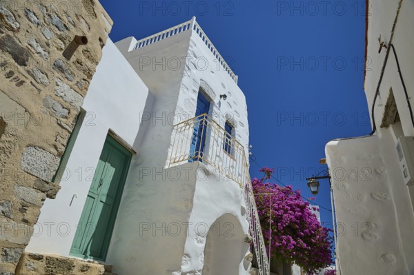 Traditional building with white walls and flowers under a bright blue sky, Chora, Astypalea,