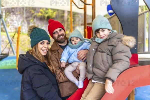 Smiling family bundled in winter clothes, enjoying quality time together while playing on a