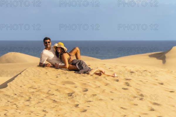 Couple relaxing on the warm sand of maspalomas dunes, enjoying the stunning ocean view and creating
