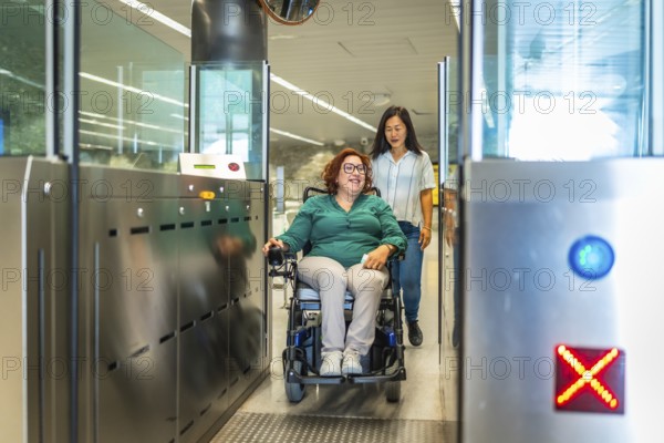 Smiling caucasian adult disabled woman in a wheelchair and chinese caregiver exiting the metro
