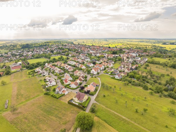 Overview of a residential area with many houses and streets, surrounded by wide fields under a