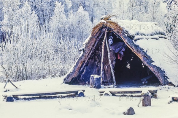 Reconstruction of a Stone Age settlement with a grass hut with snow and frost a cold winter day,